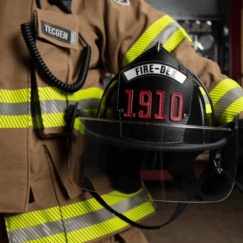 Close-up of a firefighter holding a Fire-Dex® Traditional Helmet in black by their side, showing helmet size, shape, and ergonomic design.