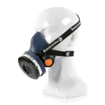 Sundström® SR 100 M/L half mask respirator with a navy blue silicone facepiece, shown on a mannequin head with black Sundström-branded adjustable head straps, a black side-mounted filter cartridge with barcode label, and an orange exhalation valve cover.
