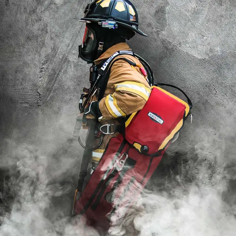 Side view of firefighter carrying True North Gear L-3 Lite Speed™ RIT Bag with padded shoulder straps and reflective safety markings during emergency response.