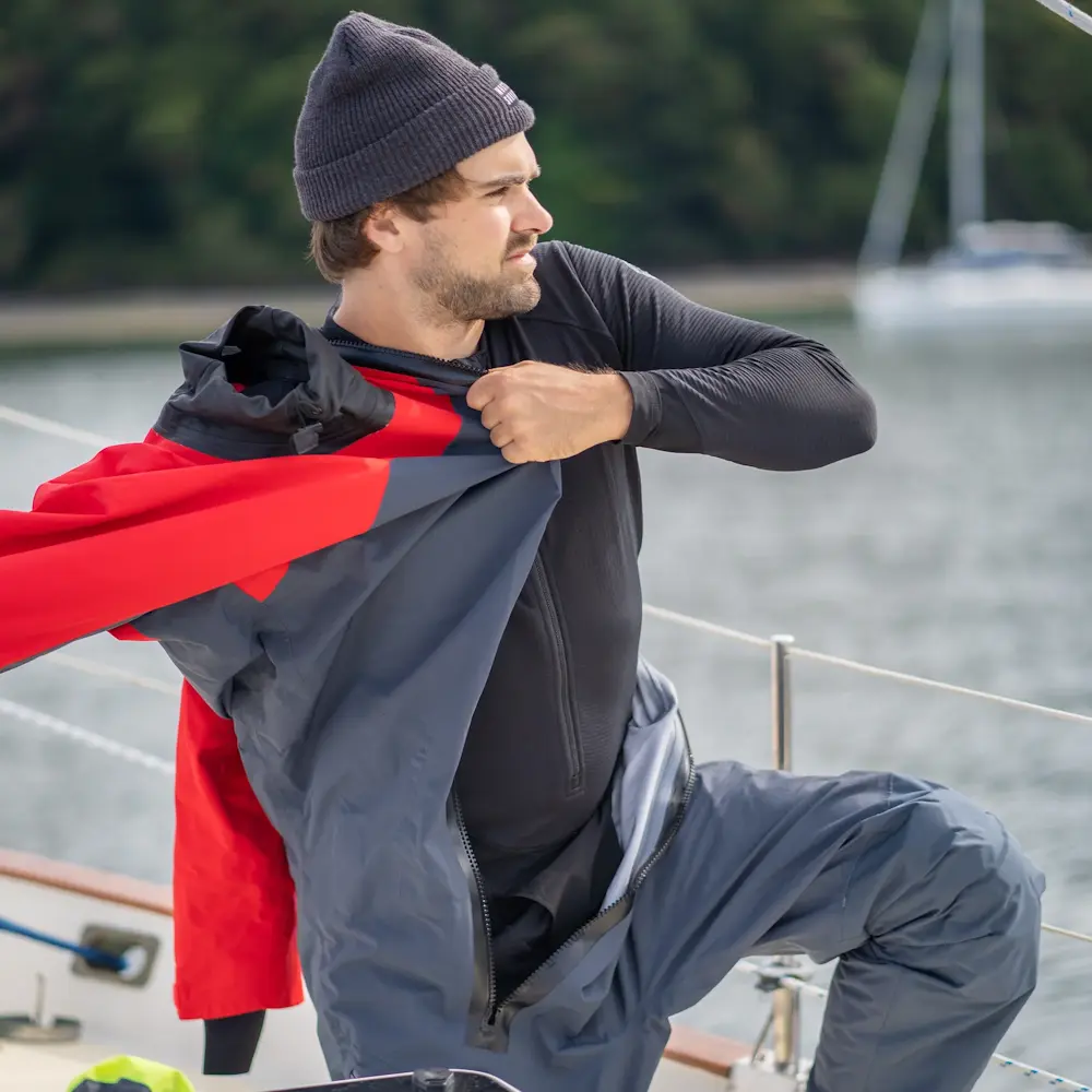Man pulling on the sleeves of a dry suit over a Mustang Survival® Men’s Kazan Dry Suit Liner for a secure and insulated fit.