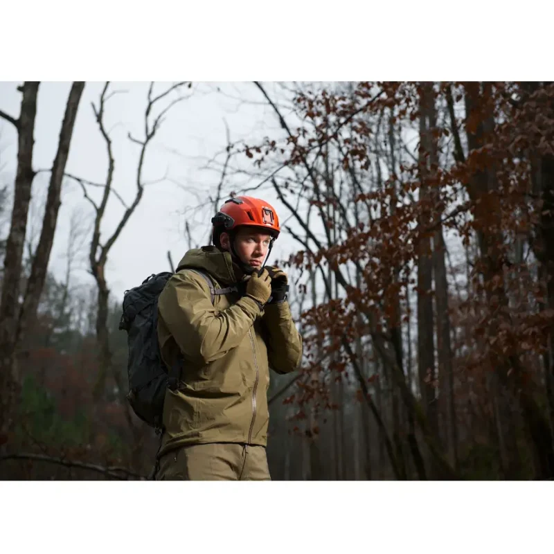 Person hiking in forest wearing Team Wendy® SAR™ Tactical Helmet in red, demonstrating durable, lightweight head protection for outdoor tactical use.