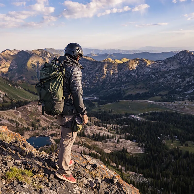 Hiker wearing Team Wendy® SAR™ Backcountry Helmet while trekking outdoors on rugged trails, showcasing lightweight and durable protective gear for outdoor adventures.