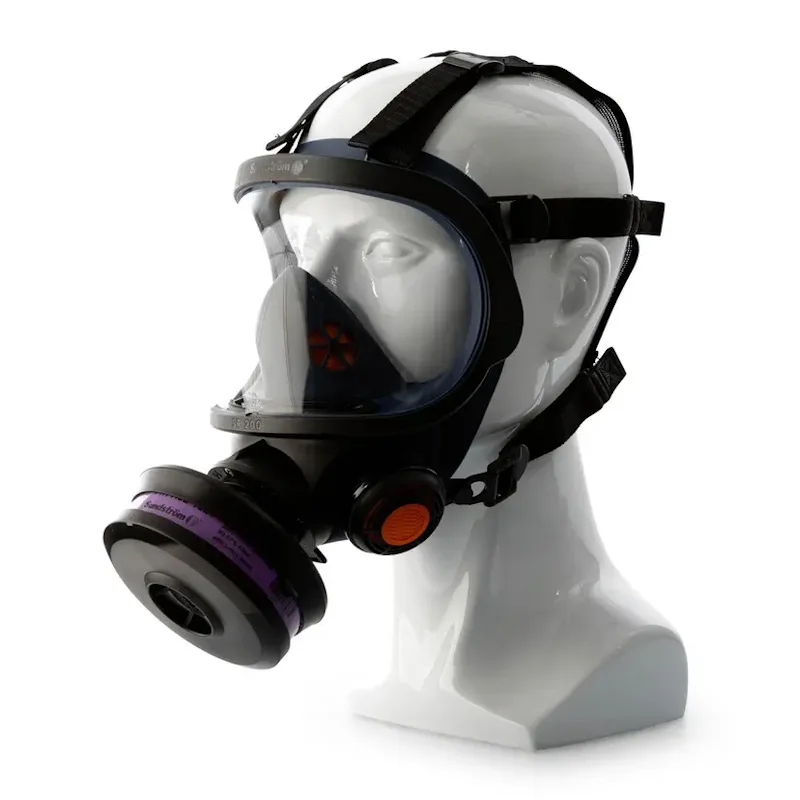 Sundström® SR 200 full face mask in black with a wide clear polycarbonate lens and inner nose cup, shown on a mannequin head with adjustable head straps, a purple-banded filter cartridge on the side, and an orange exhalation valve cover.