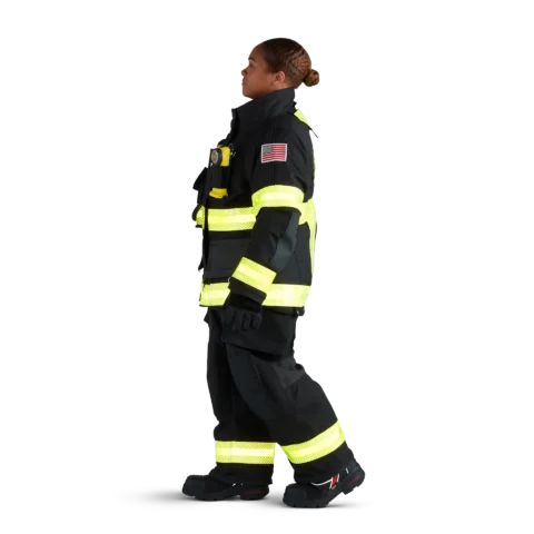 Side view of firefighter wearing black Fire-Dex® AeroFlex™ turnout gear, showing protective jacket and pants designed for heat resistance and flexibility.