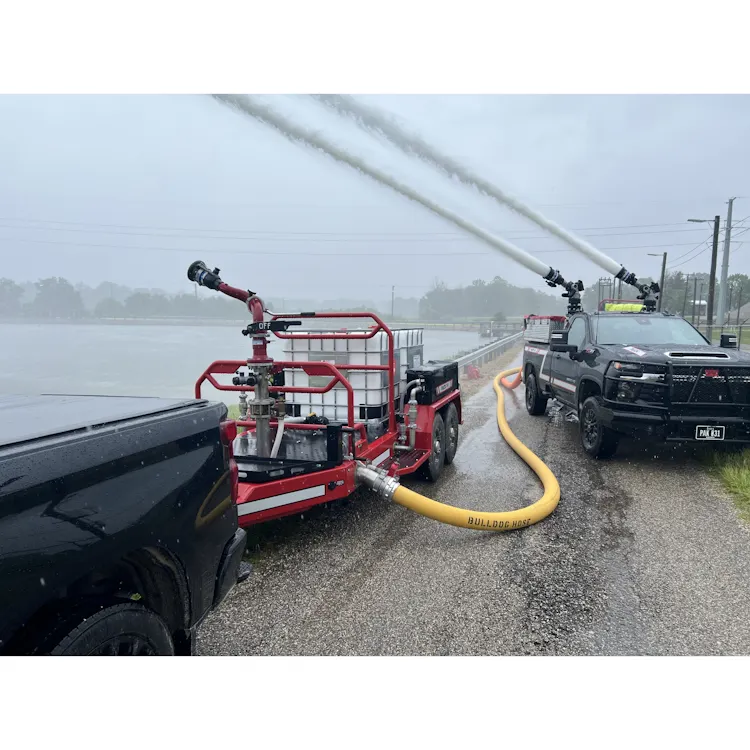 Yellow BullDog™ Hi-Vol® firefighting hose supplying a trailer-mounted water monitor and a truck-mounted monitor spraying large streams of water.