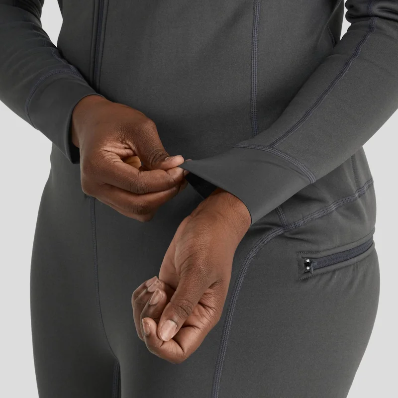 Closeup of a woman wearing the NRS Women’s Expedition Weight Union Suit, pulling on a wrist cuff to show the snug, flexible fit and fleece-lined interior.