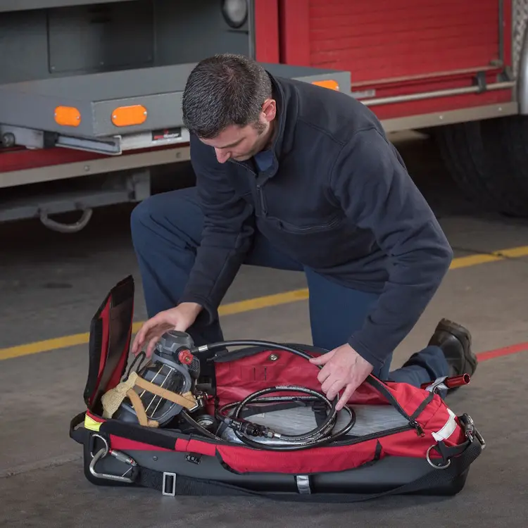 True North Gear L-3 Lite Speed™ RIT Bag resting on the ground with compartments open, revealing firefighting rescue equipment and organized storage.