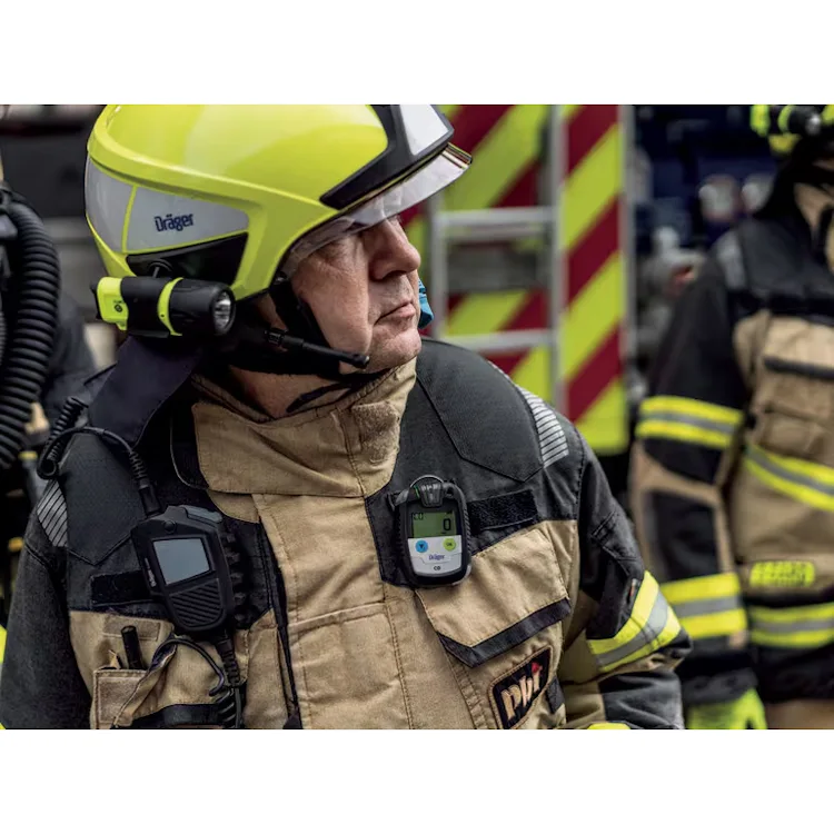 Firefighter in a yellow Dräger helmet and tan turnout gear wearing a Dräger Pac® 8500 Single-Sensor Gas Detector clipped to the chest.