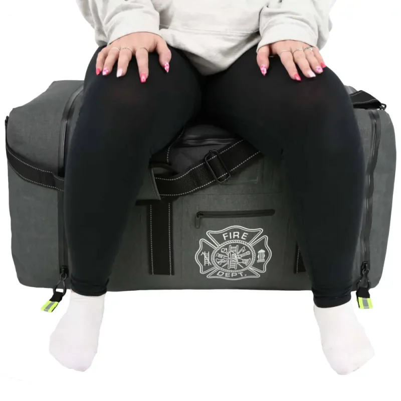 Front view of person sitting on Lightning X LXFB99 Carcinogen Resistant Dry Turnout Bag, illustrating strength and durability.