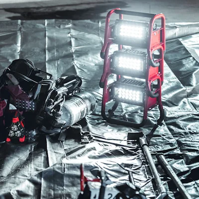 Stack of three red Streamlight® Portable Scene Light II units with their 18-LED panels lit, set on a silver tarp beside rescue equipment and tools laid out at a night work site.