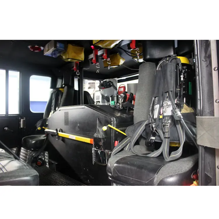 Two empty Ziamatic™ EZ-LOC Mechanical Brackets with Fixed Top Clamps mounted far apart on each side of a firetruck interior, each equipped with shoulder carrying straps and ready to securely hold cylinders for emergency response.