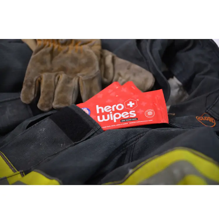 Multiple Hero Wipes® Individually Wrapped XL Body Wipes neatly placed in a firefighter’s front pocket, highlighting their compact, portable packaging for easy access and quick cleansing during emergency response.