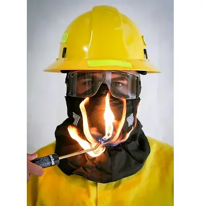 Front view of a person wearing the Hot Shield® HS-2 Wildland Firefighter Face Mask, demonstrating its flame-resistant properties as a flame is applied to the fabric without ignition or damage.