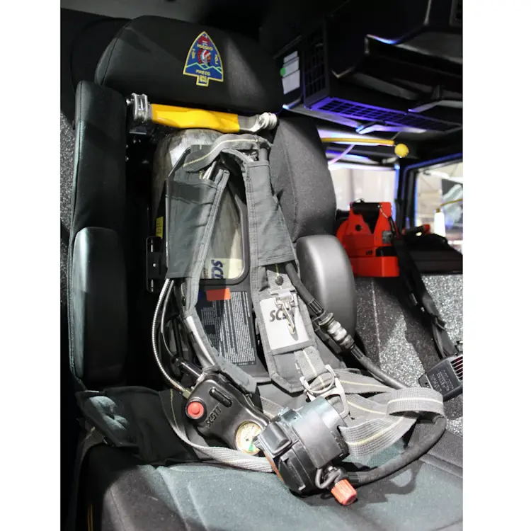 Empty Ziamatic™ ROL-LOC Mechanical Bracket with shoulder carrying straps mounted on a firetruck seat, ready to securely hold a cylinder for quick access during emergencies.
