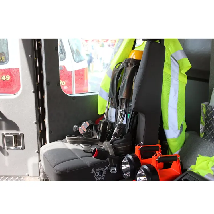 Ziamatic™ EZ-LOC Mechanical Bracket with Fixed Top Clamp mounted on a firetruck seat, equipped with shoulder carrying straps and ready to securely hold a cylinder for quick deployment during emergencies.