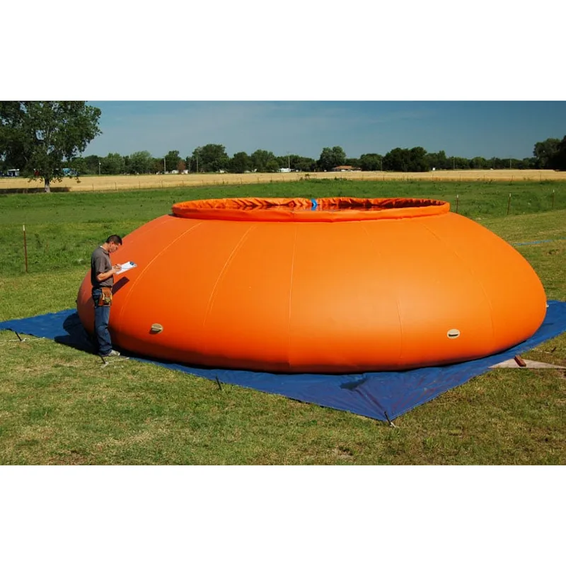Large orange Husky® self-supporting frameless portable water tank on a blue ground tarp in a grassy field with a person beside it holding a clipboard.