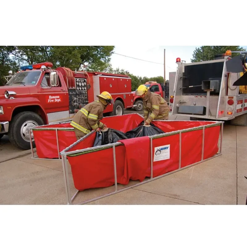 Firefighters folding and packing away a Classic Husky® Portable Folding Frame Water Tank, demonstrating its compact storage and ease of transport after use in firefighting operations.