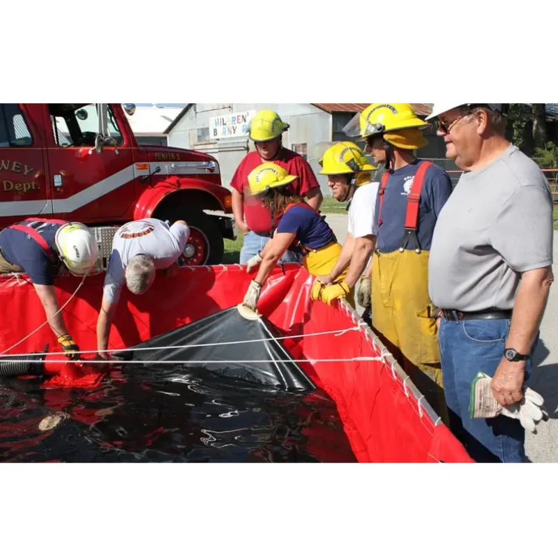 Firefighters utilizing a Classic Husky® Portable Folding Frame Water Tank, standing beside it during active water storage operations in firefighting and emergency response.