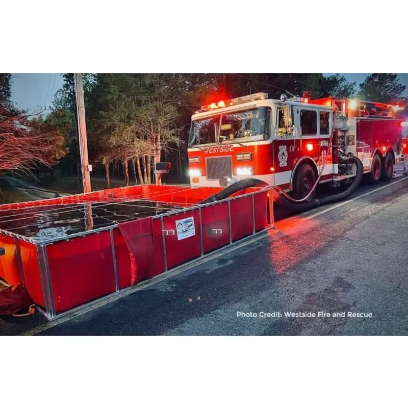 A fire truck filling a Classic Husky® Portable Folding Frame Water Tank, demonstrating efficient water supply setup during firefighting operations.