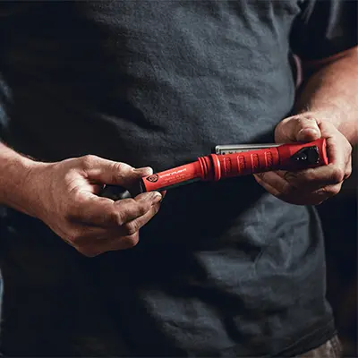 Person holding the Streamlight® Strion Switchblade® flashlight, demonstrating its unique dual-head foldable design that allows quick switching between flood and spot beam modes for versatile lighting.