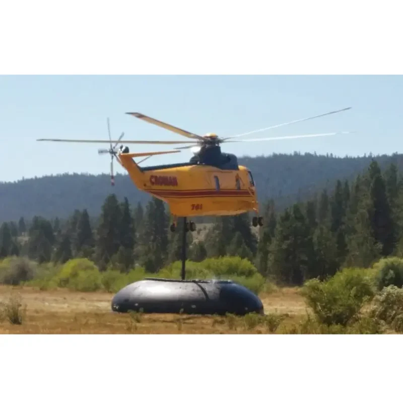 Distant view of a Husky® Self-Supporting Frameless Portable Water Tank supplying water for helicopter refueling during firefighting operations, demonstrating its reliable and portable water storage capability.