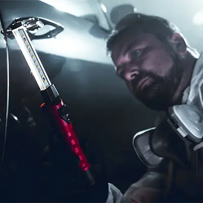 Person using the Streamlight® Strion Switchblade® flashlight, unfolding the dual-head design to switch between flood and spot beams for precise illumination in tactical or emergency situations.