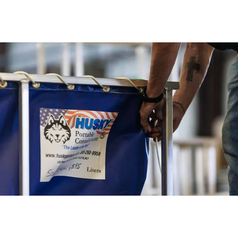 Person tightening the rope lacing on a blue Husky® aluminum or steel frame decontamination pool with a Husky® Portable Containment label.