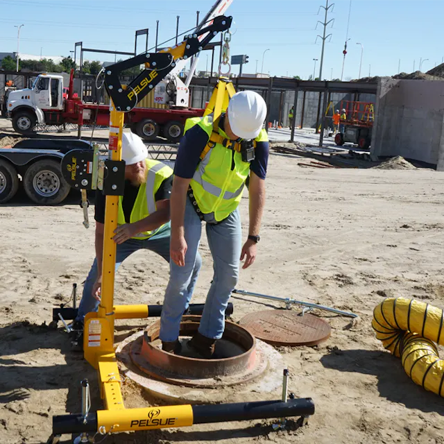 Pelsue® Portable Davit Fall Protection System safely lowering a worker into a manhole, featuring a sturdy aluminum davit arm and secure anchoring for controlled descent and fall protection during confined space entry.