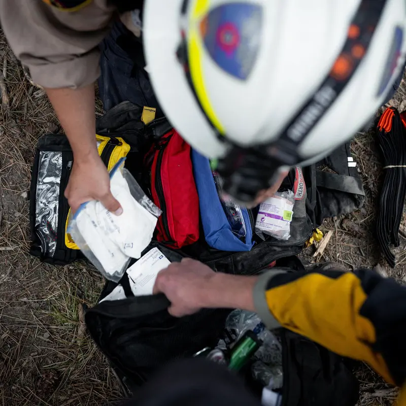 Firefighters retrieving medical supplies from the True North Gear Firefly™ Medic Pack, demonstrating its practical layout and rapid-access design for use in high-pressure emergency and wildfire response scenarios.