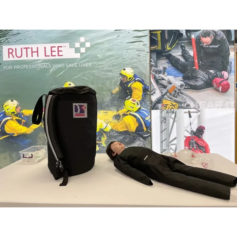 A Ruth Lee™ Advanced Water Rescue Toddler manikin showcased on a table with visible branding, used for promotional and training demonstration purposes.
