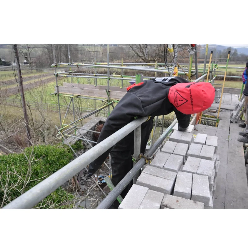 Here’s an optimized and accessible image description for that scene: A Ruth Lee™ Multi Trauma Training Manikin positioned lying across a railing, simulating a severely injured casualty in a high-risk rescue training scenario.
