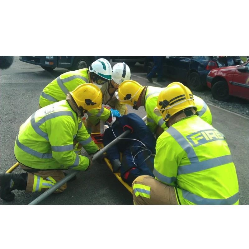 A rescue team carefully placing a Ruth Lee™ Multi Trauma Training Manikin with impalement injuries onto a stretcher during a simulated emergency trauma extraction exercise.