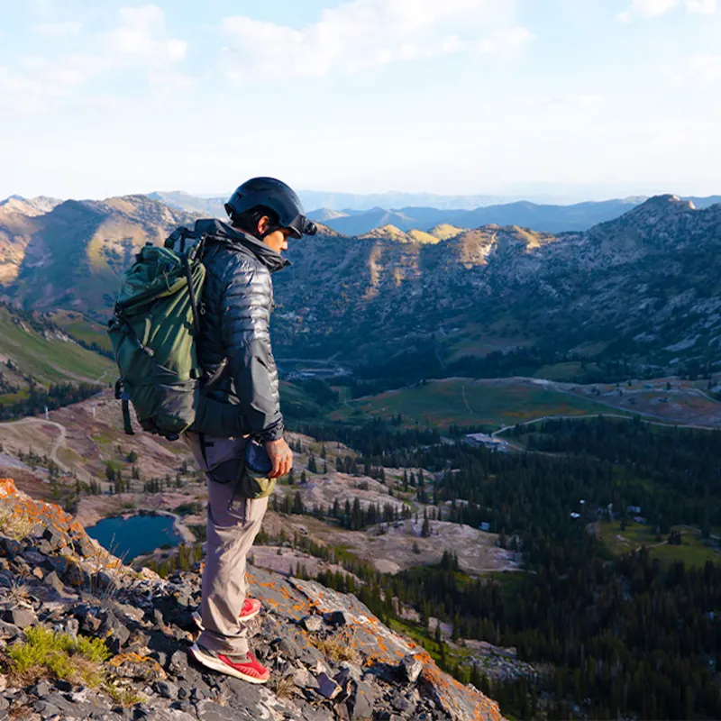 Hiker wearing Team Wendy® ADVENTURER™ Bump Helmet, overlooking a mountain ridge with backpack and trekking gear.