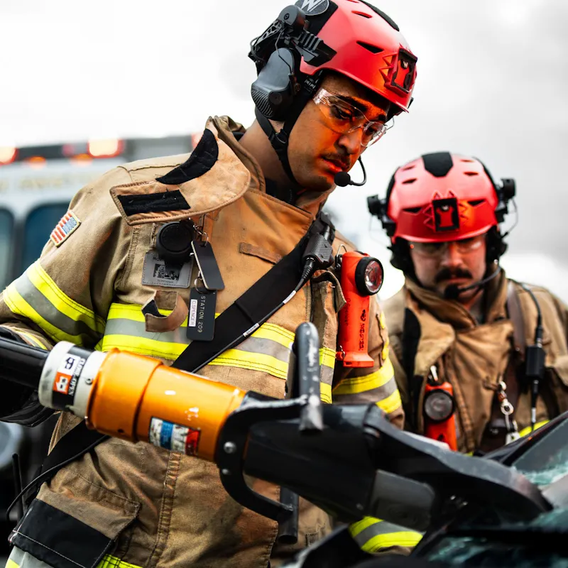Firefighters wearing Team Wendy® EXFIL® Rescuer Bump Helmets in red with headsets during vehicle extrication.